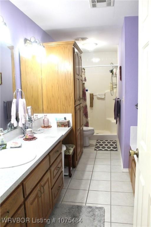 bathroom featuring a shower, vanity, tile patterned floors, and toilet