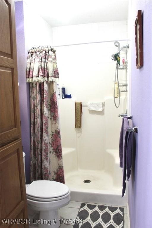 bathroom with tile patterned floors, curtained shower, and toilet