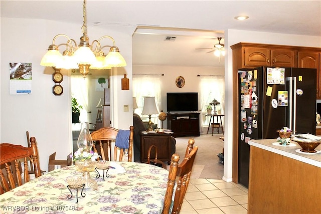 dining room featuring light tile patterned floors and ceiling fan with notable chandelier