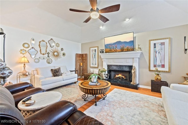 living room featuring hardwood / wood-style floors, ceiling fan, and a premium fireplace