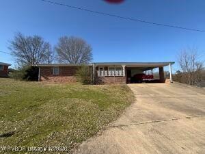 view of front of home featuring a carport, concrete driveway, and a front lawn