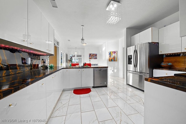 6408 Southfield Dr, Fort Smith, AR 72916 - kitchen with white cabinets, a peninsula, marble finish floor, stainless steel appliances, and hanging light fixtures