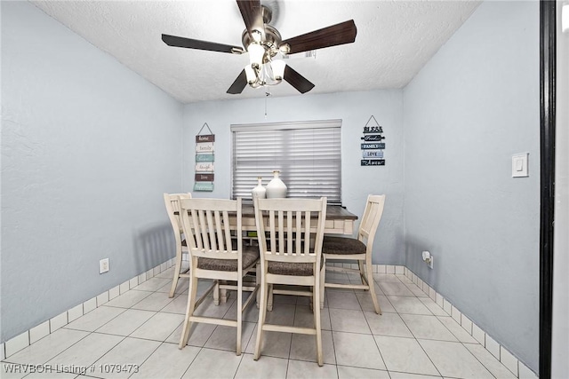 dining room featuring light tile patterned floors, baseboards, a textured ceiling, and a ceiling fan