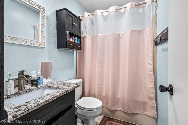 full bath with toilet, shower / bath combo, vanity, and a textured wall