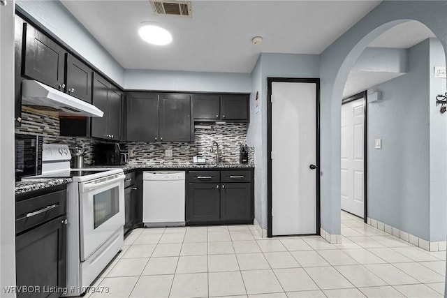 kitchen featuring white appliances, visible vents, a sink, under cabinet range hood, and backsplash