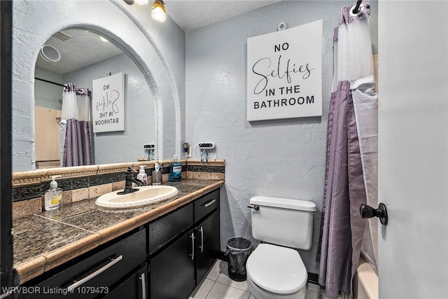 bathroom featuring vanity, visible vents, tile patterned flooring, toilet, and a textured wall