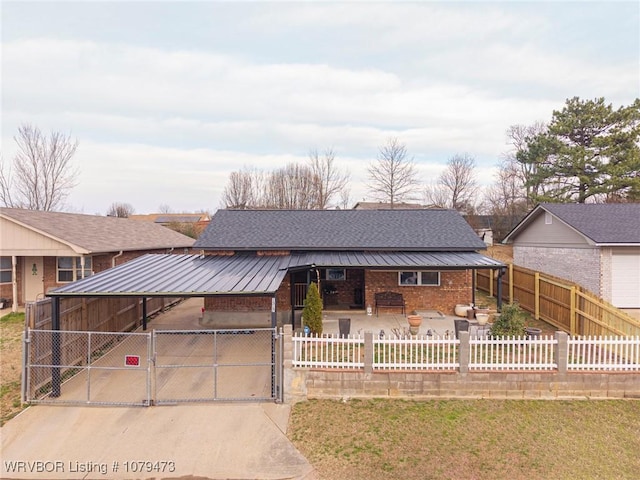 view of front facade featuring brick siding, fence private yard, metal roof, a patio area, and a gate