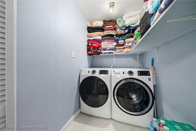 washroom featuring laundry area, baseboards, and washer and clothes dryer