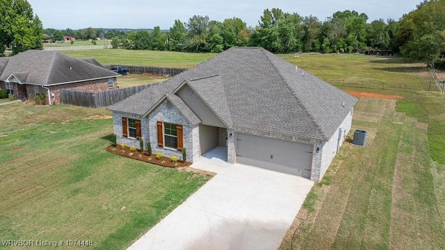 view of front of home with a garage, a front yard, and central AC