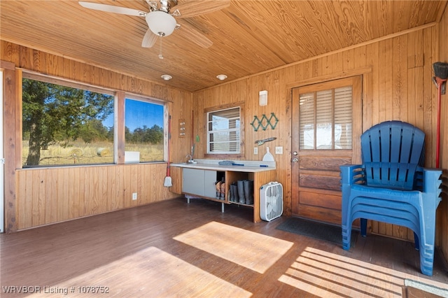 sitting room with ceiling fan, wood walls, dark hardwood / wood-style floors, and wooden ceiling