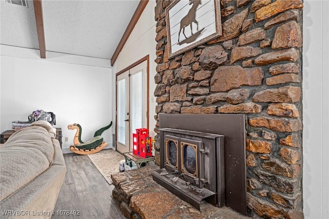 unfurnished living room with a textured ceiling, a wood stove, hardwood / wood-style floors, and lofted ceiling with beams