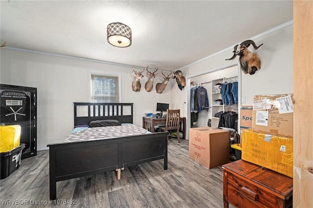 bedroom featuring a closet, a textured ceiling, ornamental molding, and wood-type flooring