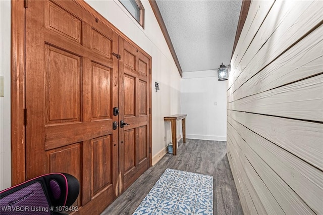 hallway with vaulted ceiling, dark hardwood / wood-style floors, and a textured ceiling