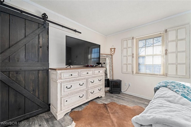 bedroom with hardwood / wood-style flooring, ornamental molding, and a barn door