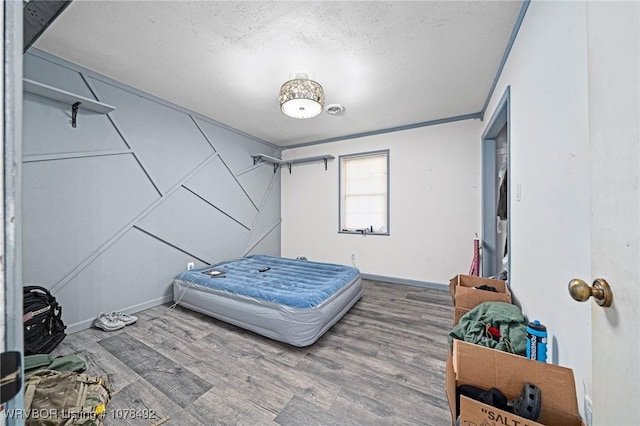 bedroom featuring wood-type flooring, a textured ceiling, and ornamental molding