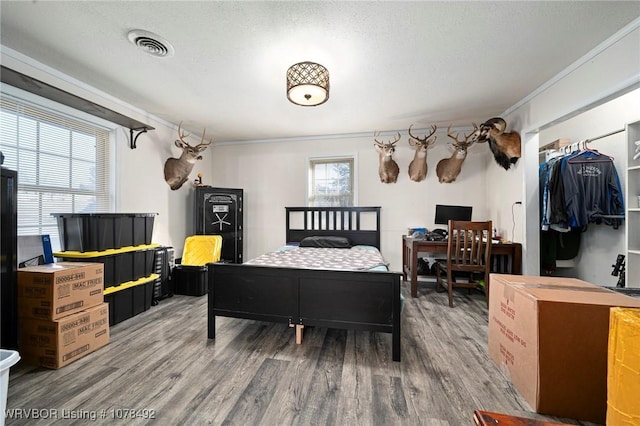 bedroom featuring a textured ceiling, crown molding, and wood-type flooring