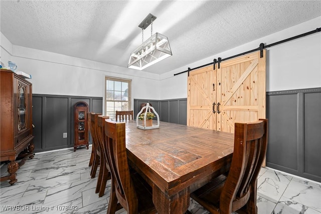 dining area with a textured ceiling and a barn door