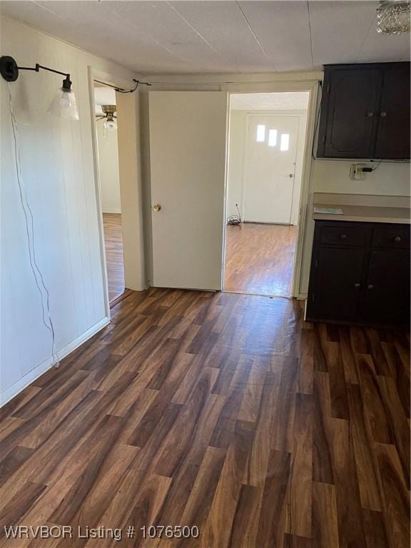 interior space with ceiling fan, dark brown cabinetry, and dark wood-type flooring