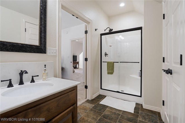 bathroom with a shower with door, vanity, and vaulted ceiling