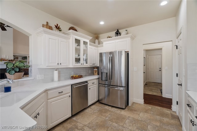 kitchen featuring backsplash, white cabinetry, sink, and appliances with stainless steel finishes