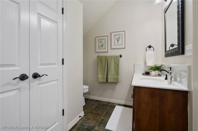 bathroom with vanity, lofted ceiling, and toilet