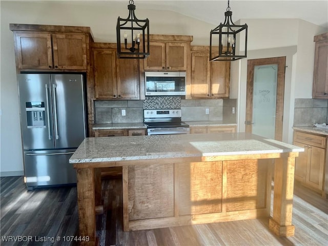 kitchen with decorative light fixtures, an inviting chandelier, appliances with stainless steel finishes, and vaulted ceiling