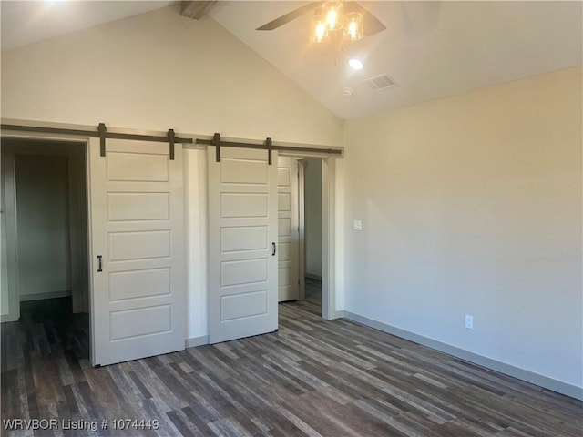 unfurnished bedroom featuring vaulted ceiling with beams, a barn door, dark hardwood / wood-style floors, and ceiling fan