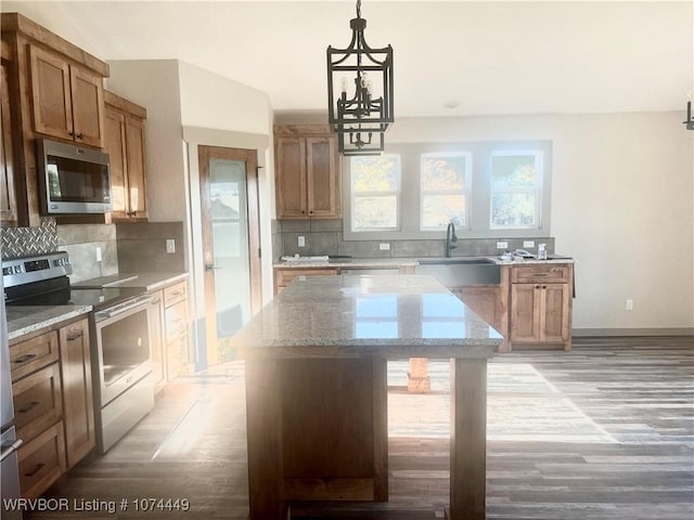 kitchen featuring appliances with stainless steel finishes, sink, light hardwood / wood-style flooring, a center island, and hanging light fixtures