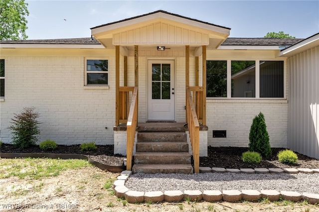 property entrance featuring brick siding and a shingled roof