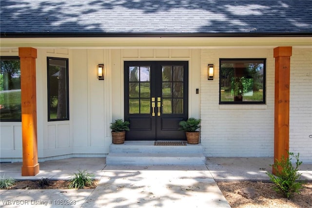 6001 Bolton Rd, Fort Smith, AR 72903 - view of exterior entry featuring board and batten siding, a shingled roof, brick siding, french doors, and covered porch