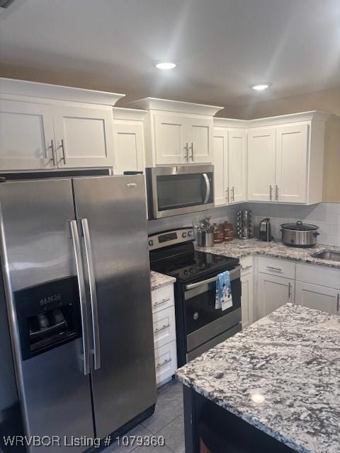 kitchen featuring light stone counters, tasteful backsplash, appliances with stainless steel finishes, white cabinets, and tile patterned floors