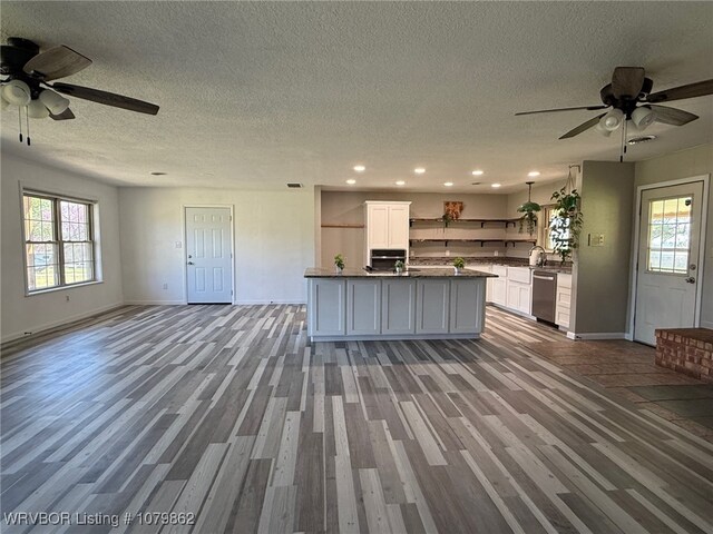 kitchen featuring open floor plan, open shelves, stainless steel dishwasher, dark countertops, and ceiling fan