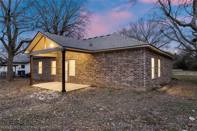 3115 Spradling Ave, Fort Smith, AR 72904 - property exterior at dusk with brick siding, a patio area, and a shingled roof