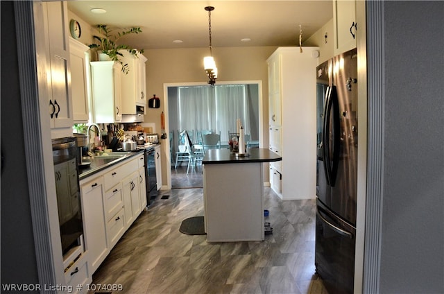 kitchen featuring sink, pendant lighting, a center island, white cabinetry, and stainless steel refrigerator