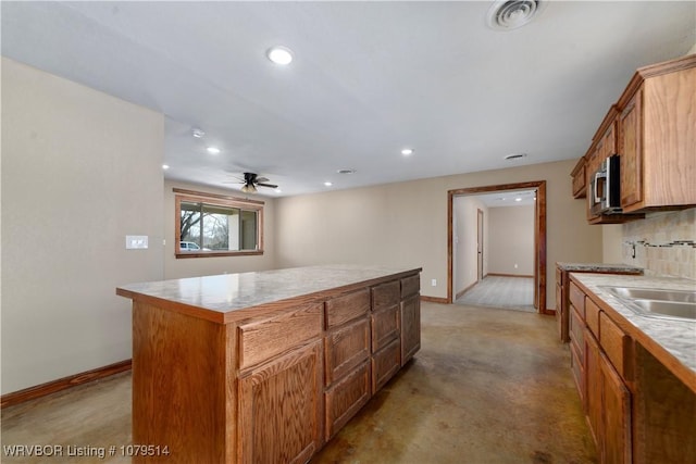 kitchen with a sink, visible vents, baseboards, and a kitchen island