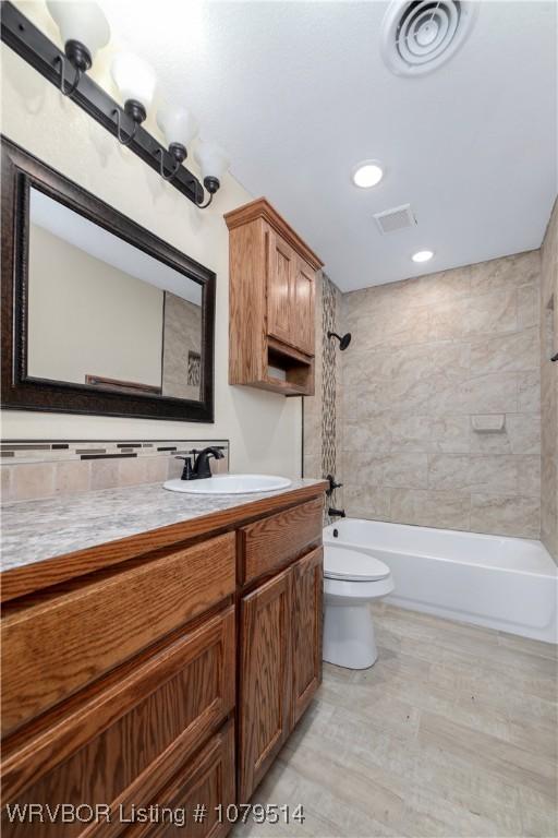 full bathroom featuring vanity, toilet, washtub / shower combination, and visible vents