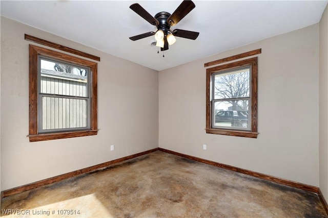 unfurnished room featuring baseboards, concrete floors, and a ceiling fan