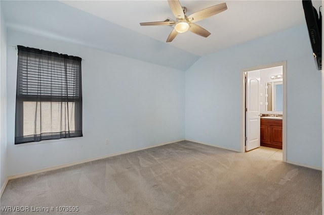 empty room featuring baseboards, light colored carpet, a ceiling fan, and vaulted ceiling