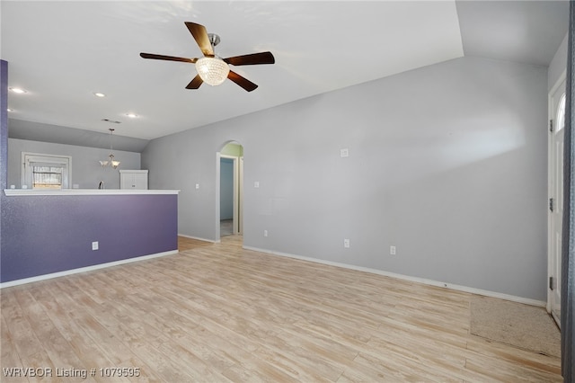 unfurnished living room featuring baseboards, light wood-style floors, arched walkways, and ceiling fan