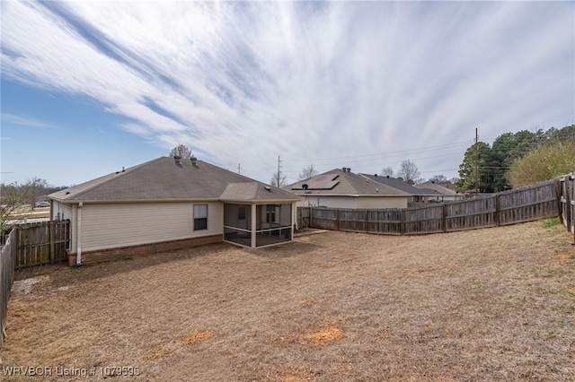 back of property featuring a fenced backyard and a sunroom