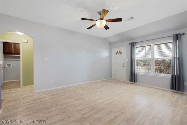 unfurnished room with visible vents, arched walkways, ceiling fan, and light wood-style flooring