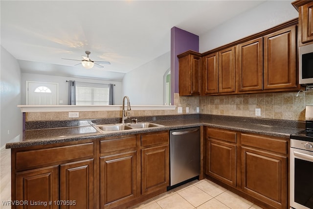 kitchen with a sink, dark countertops, decorative backsplash, and stainless steel appliances