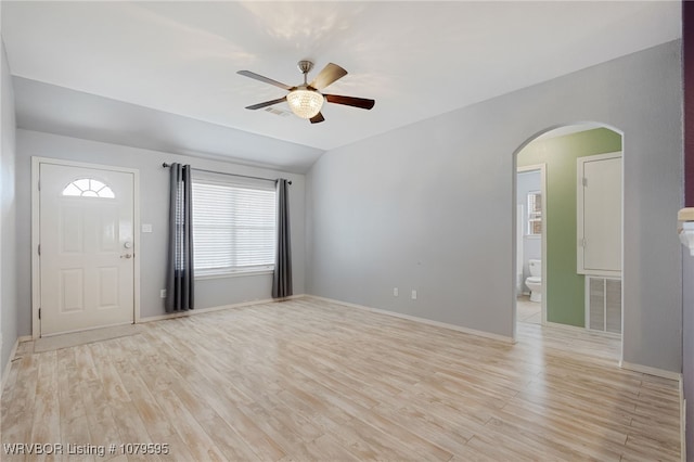 foyer entrance featuring visible vents, vaulted ceiling, light wood-style flooring, arched walkways, and a ceiling fan