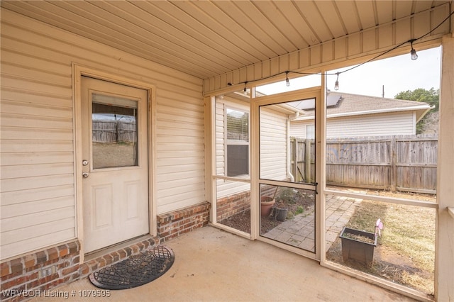 view of exterior entry with a patio area and fence