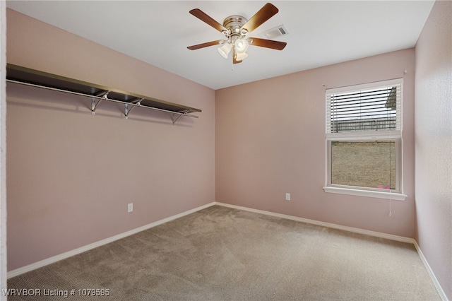 carpeted spare room with visible vents, baseboards, and a ceiling fan