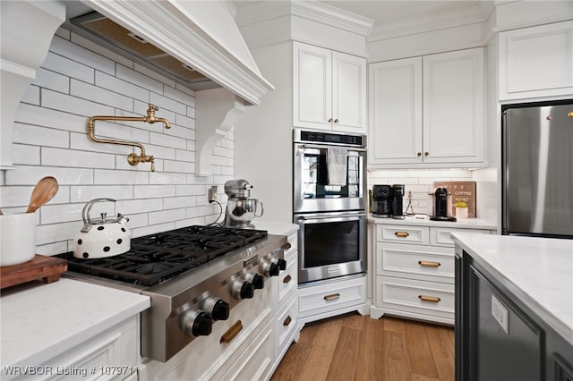 8801 Rombauer Pt, Fort Smith, AR 72916 - kitchen with white cabinetry, stainless steel appliances, crown molding, and wood finished floors