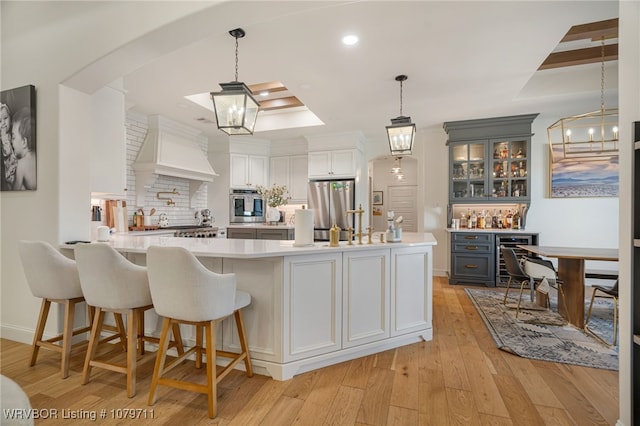 8801 Rombauer Pt, Fort Smith, AR 72916 - kitchen with custom exhaust hood, light wood-style flooring, stainless steel appliances, light countertops, and tasteful backsplash