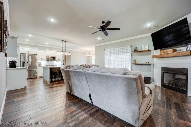 2803 Turtle Creek Dr, Lavaca, AR 72941 - living area with ornamental molding, a ceiling fan, a large fireplace, a chandelier, and dark wood-type flooring