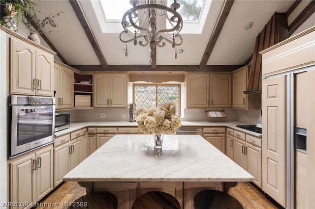 kitchen with a center island, lofted ceiling with skylight, backsplash, light hardwood / wood-style flooring, and appliances with stainless steel finishes