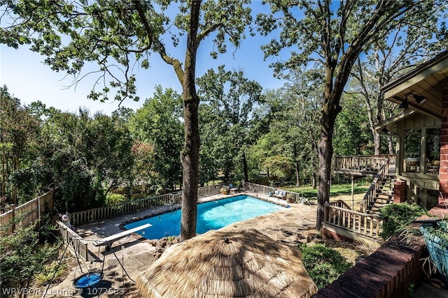 view of swimming pool featuring a diving board and a deck